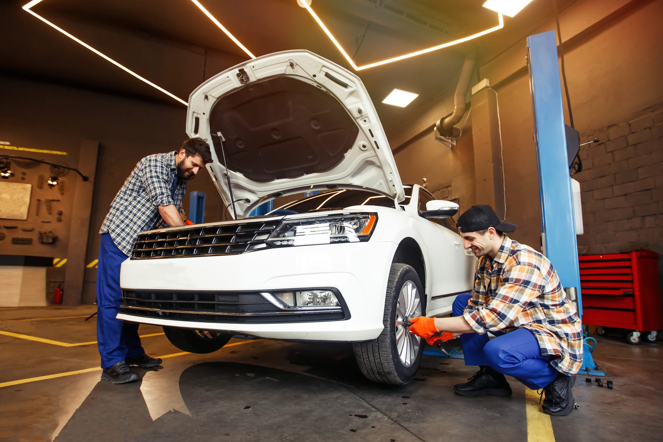 smiling mechanics repairing modern car workshop